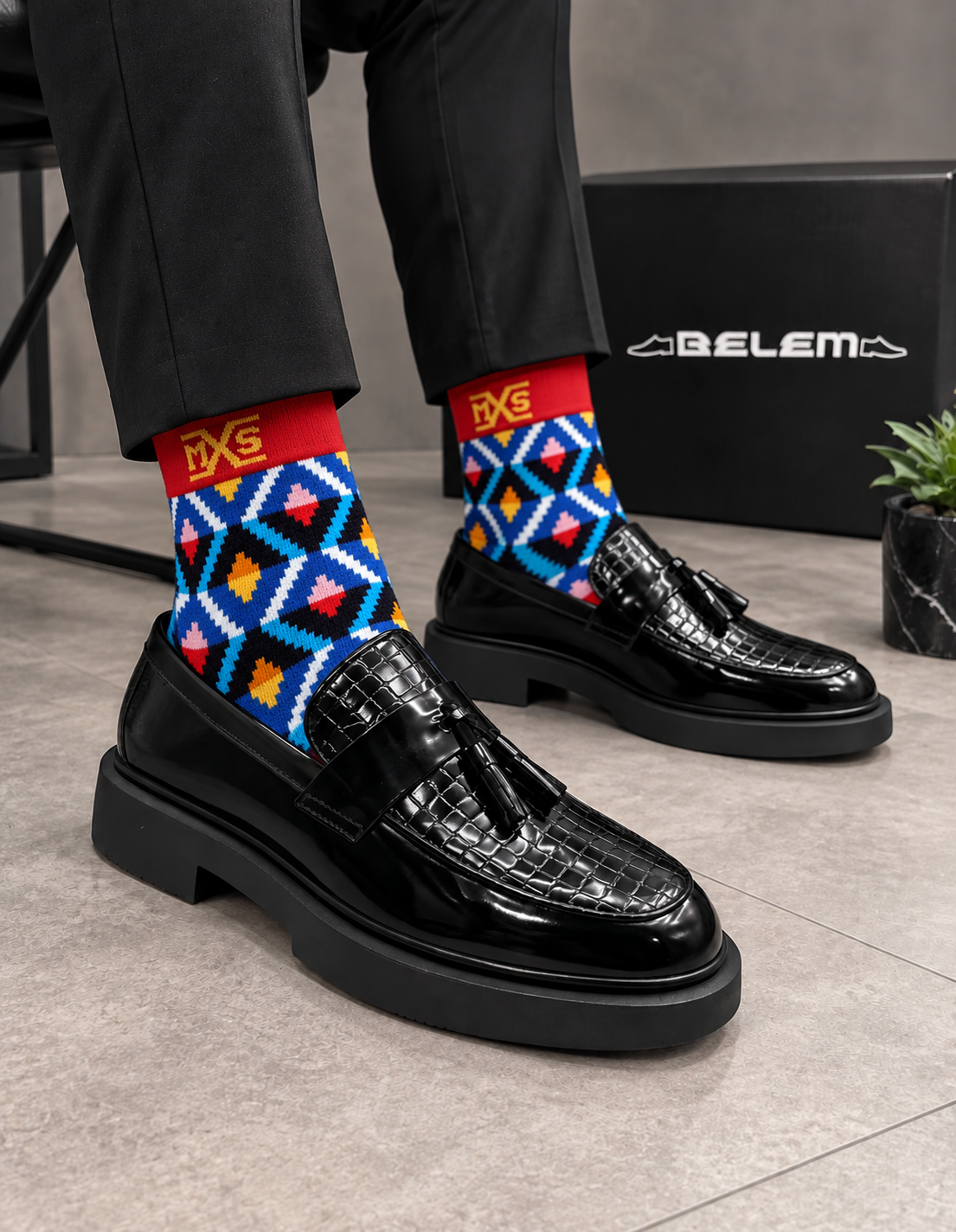 Black Belem tassel loafers styled with bold patterned socks on a polished floor