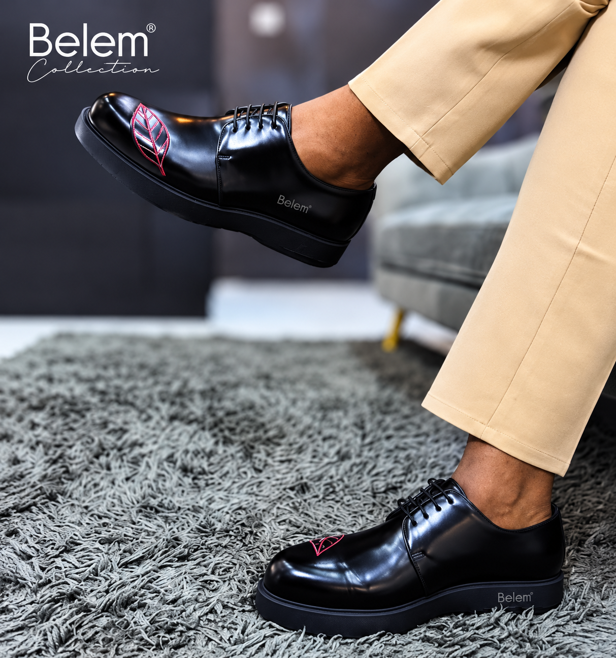 Black Belem leather derby shoes with red leaf embroidery worn with beige trousers on a grey shag rug